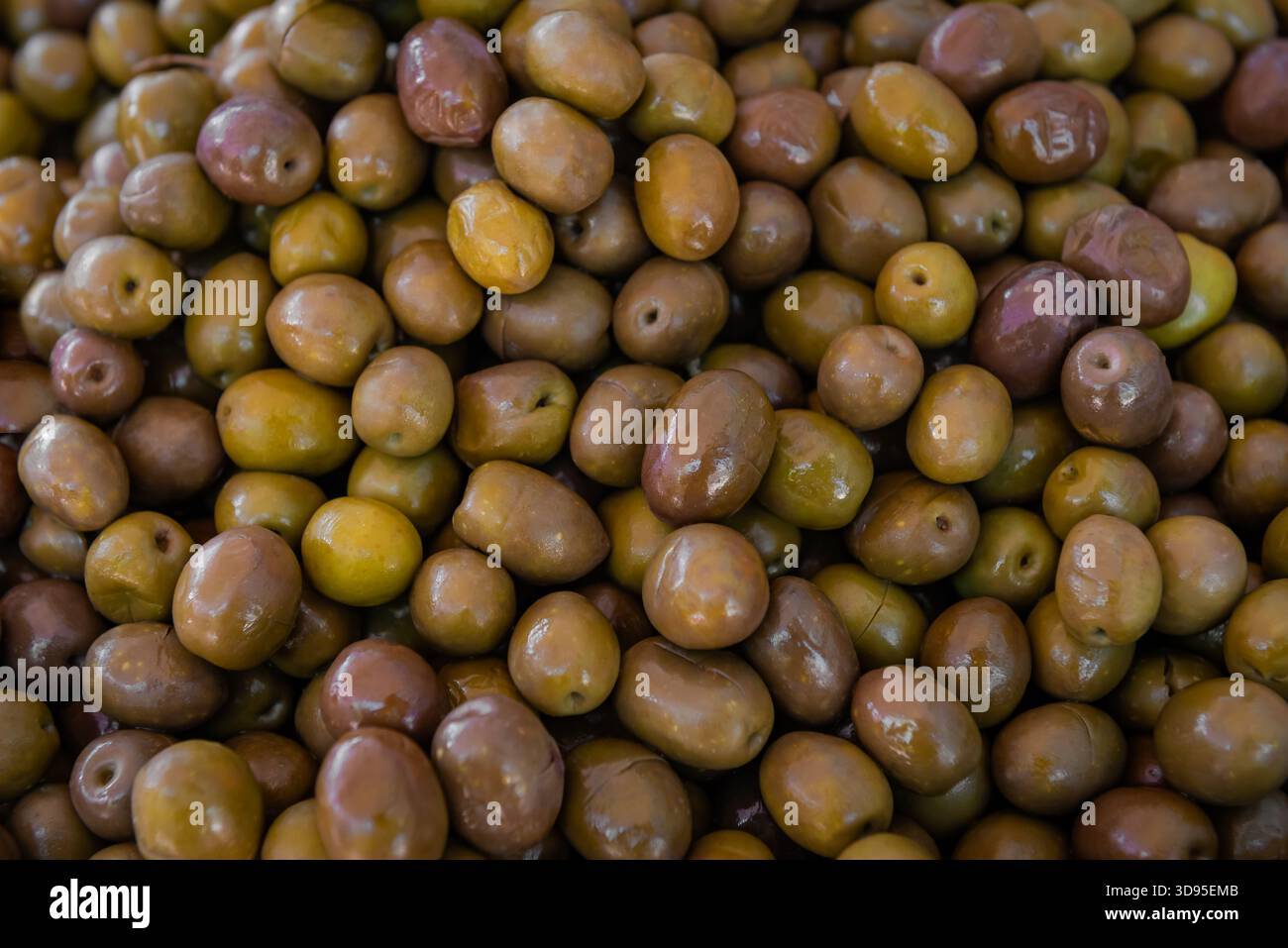 Olives vertes brillantes et brunes densément emballées ensemble, mettant en valeur la maturité, la marination et la richesse culinaire méditerranéenne en gros plan Banque D'Images
