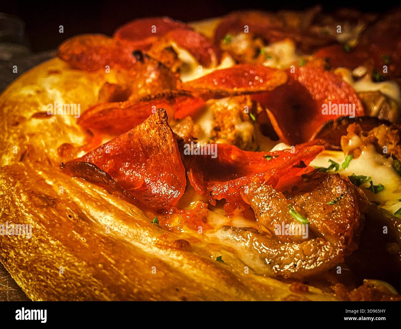 Gros plan d'une pizza au pepperoni fraîchement cuite avec une croûte dorée, du fromage mozzarella fondu et des tranches de pepperoni salées, garnies d'herbes fo Banque D'Images