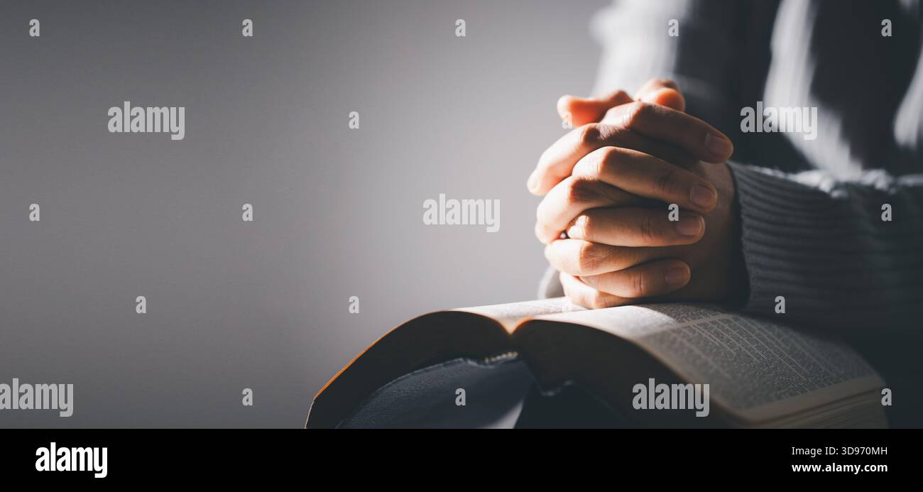 Mains pliées dans la prière sur la sainte Bible dans le concept de l'église pour la foi, la spiritualité et la religion. Femme méconnaissable tenant une Bible dans ses mains et pra Banque D'Images