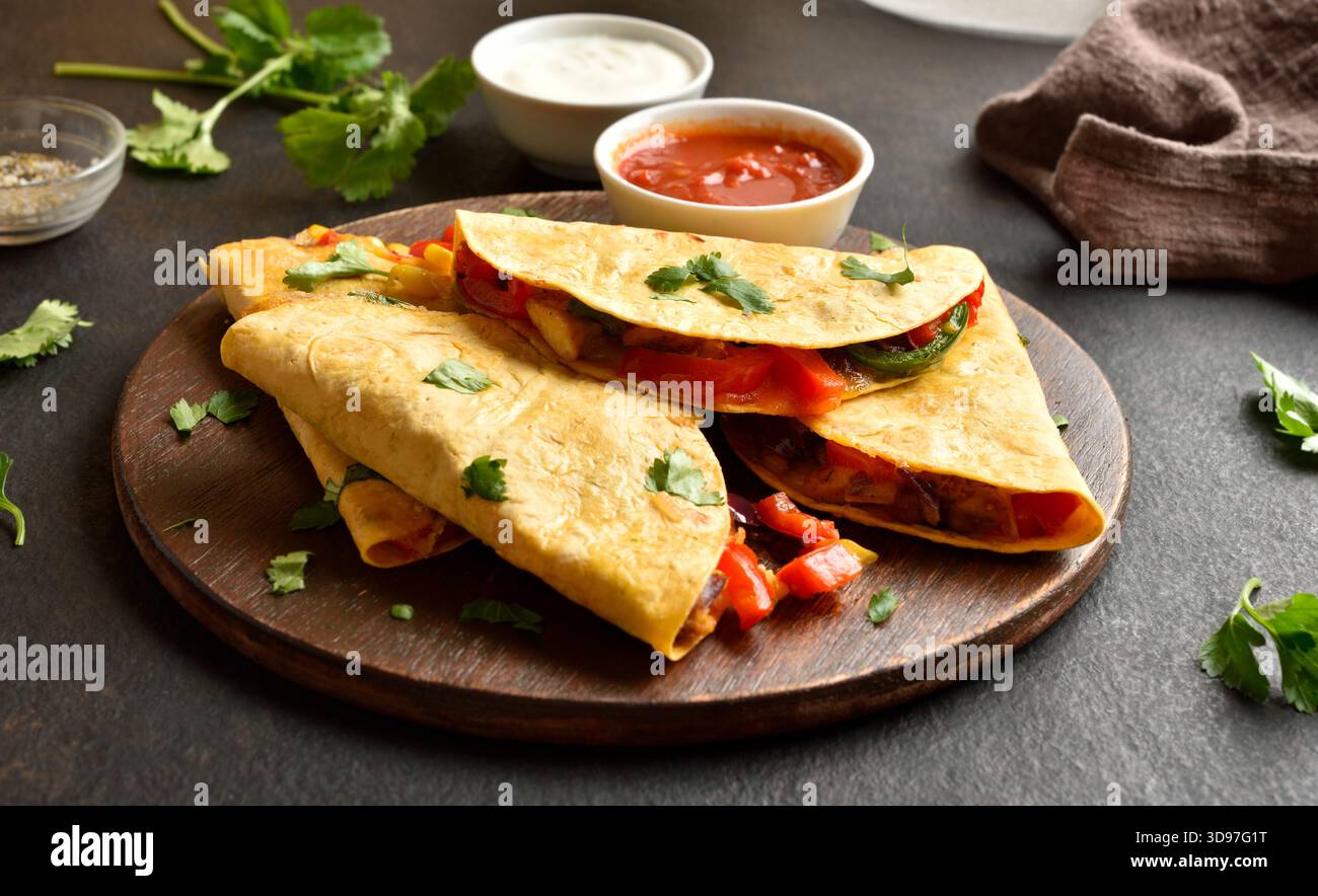 Délicieuse quesadilla aux légumes frais servie avec sauce sur un plateau en bois sur fond de pierre brune. Vue rapprochée Banque D'Images
