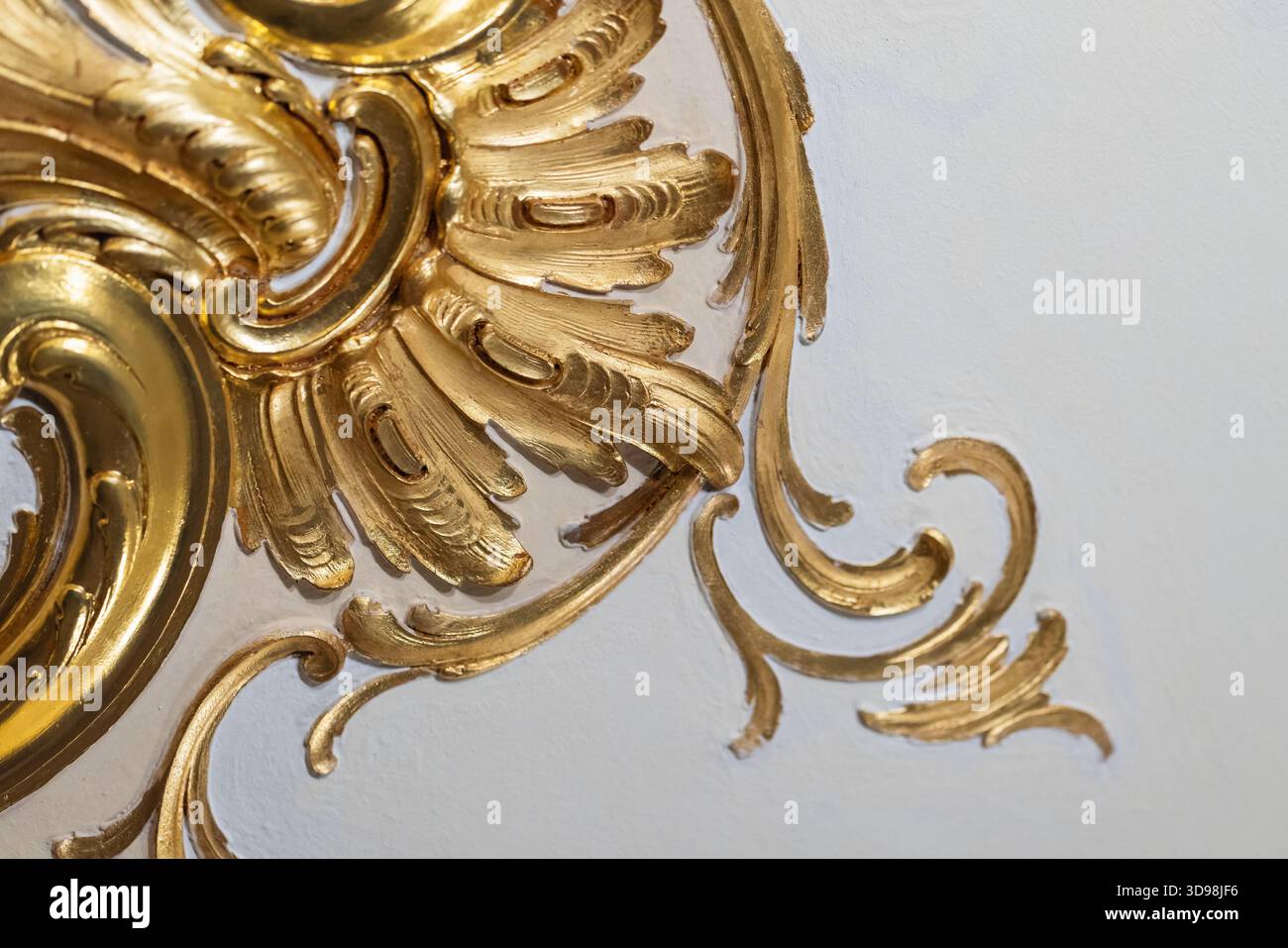 Décoration de plafond luxueuse avec volutes d'acanthe dorées et plâtre complexe sur fond blanc. Décor baroque classique crée un Banque D'Images