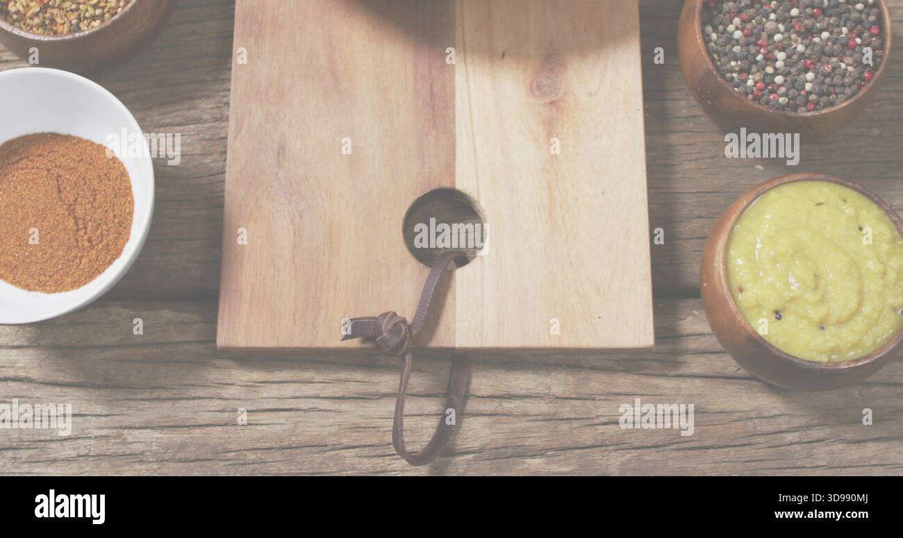 Montrant planche à découper légère avec trou rond et bracelet en cuir sur table rustique, avec bols à épices Banque D'Images