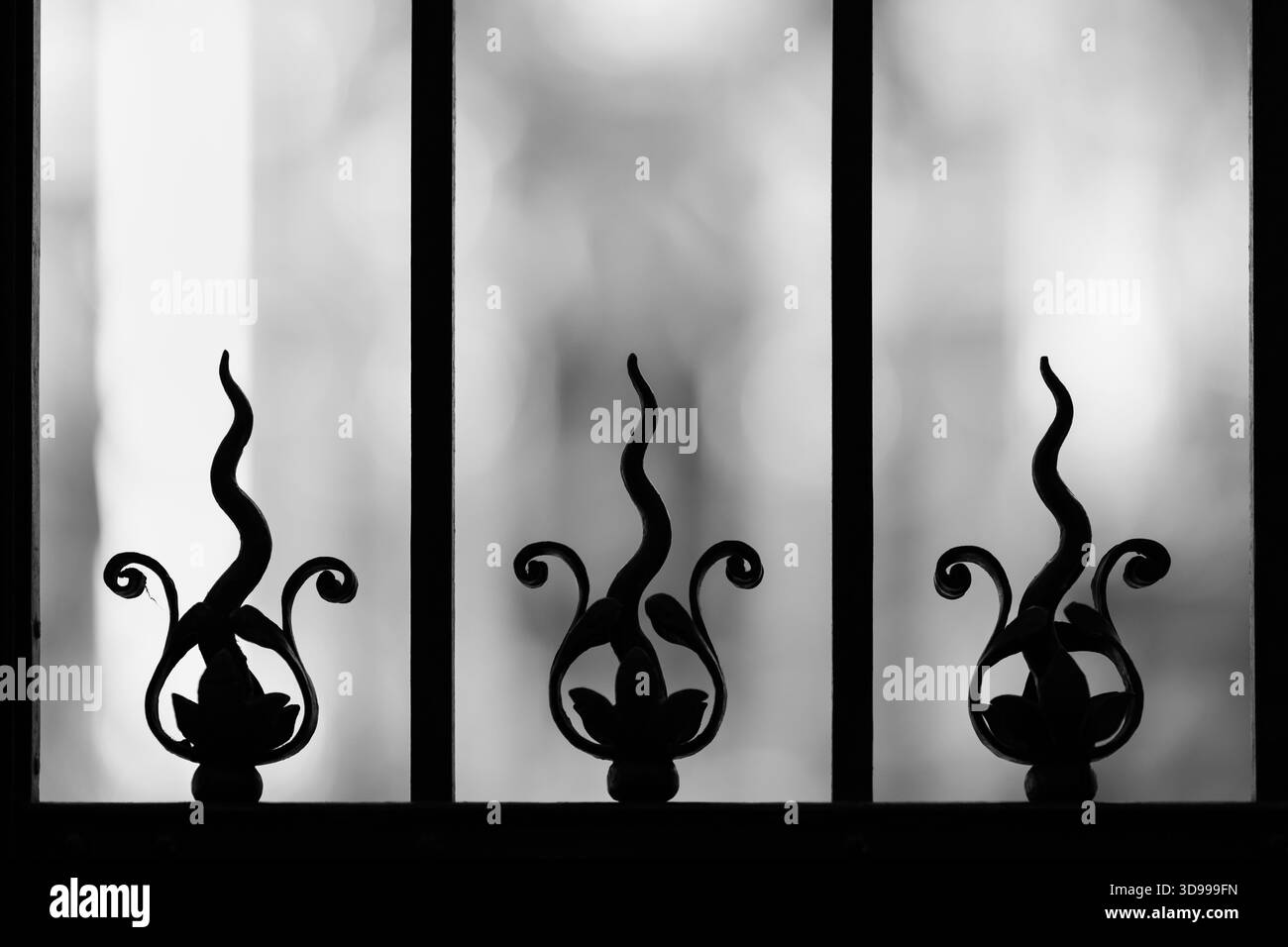 Treillis abstrait en fer forgé rétroéclairé avec des éléments semblables à des flammes dans la composition artistique noir et blanc Banque D'Images