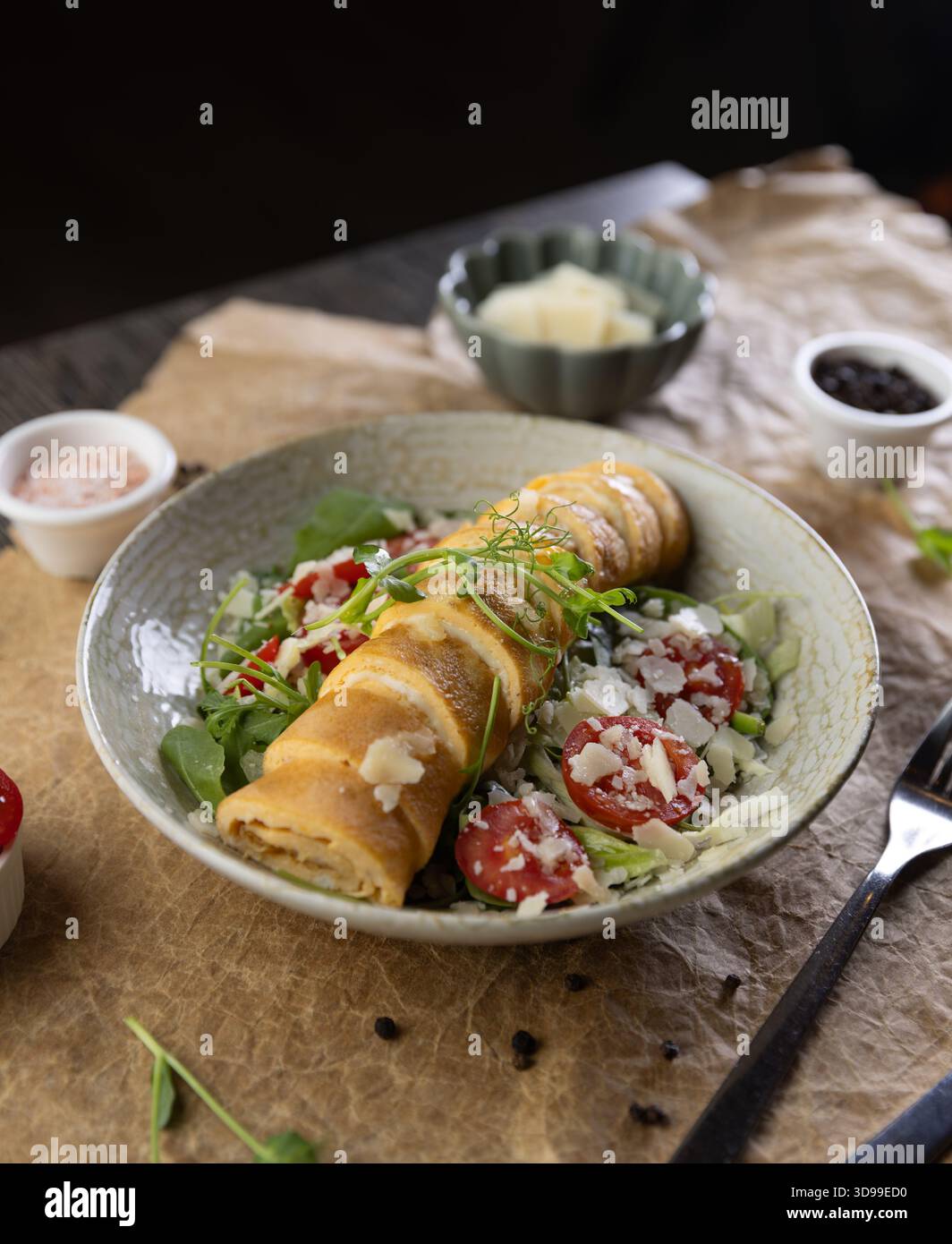 Concept de menu petit déjeuner du restaurant, omelette roulée farcie de chesse servie sur laitue fraîche Banque D'Images