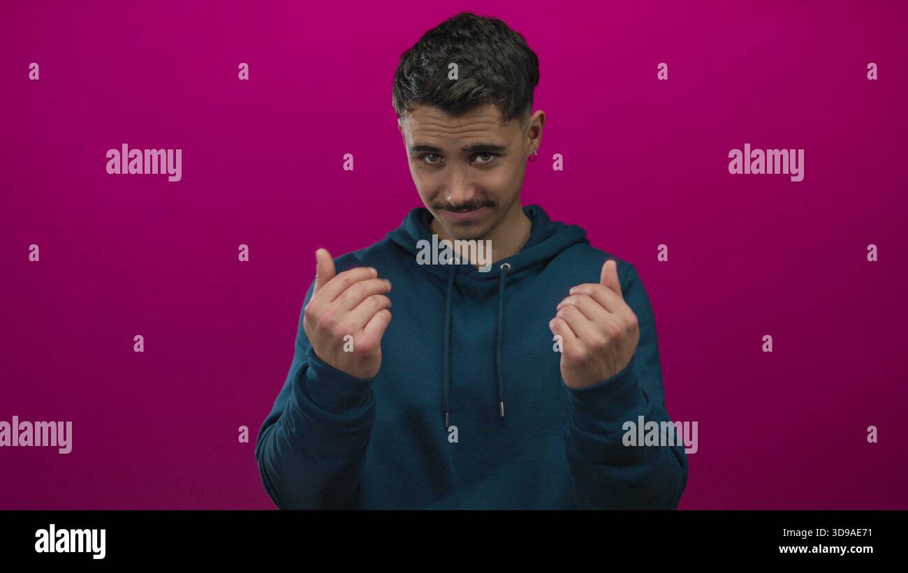 Les gestes d'un jeune homme hispanique viennent ici avec les mains sur un fond rose éclatant, apparaissant invitant et ludique dans un cliché de studio vif et isolé. Banque D'Images