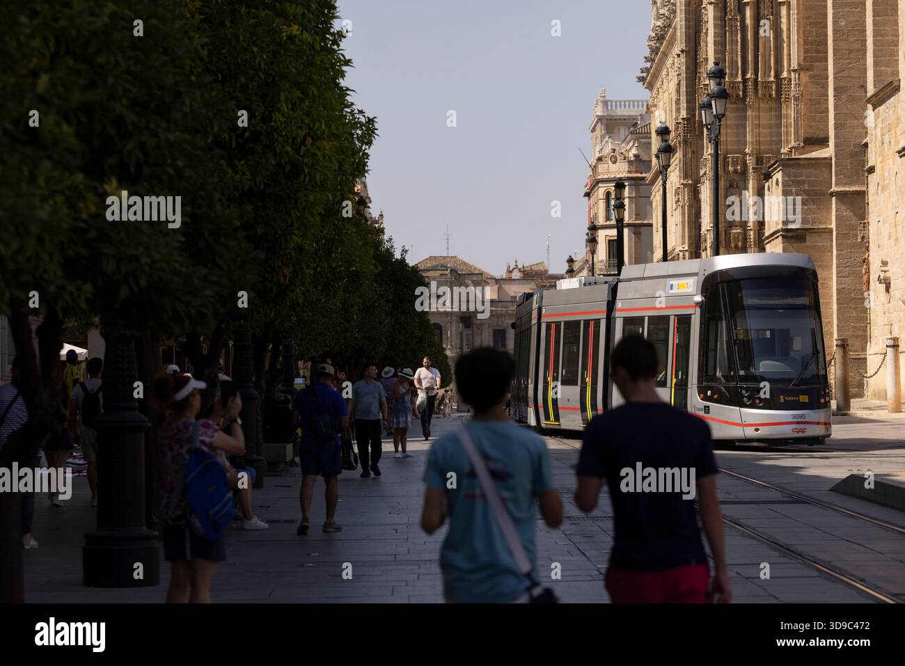 Séville, Andalousie, Espagne - 16 juillet 2025 : un train léger s'éloigne de l'arrêt de tramway Archivo de Indias. Banque D'Images