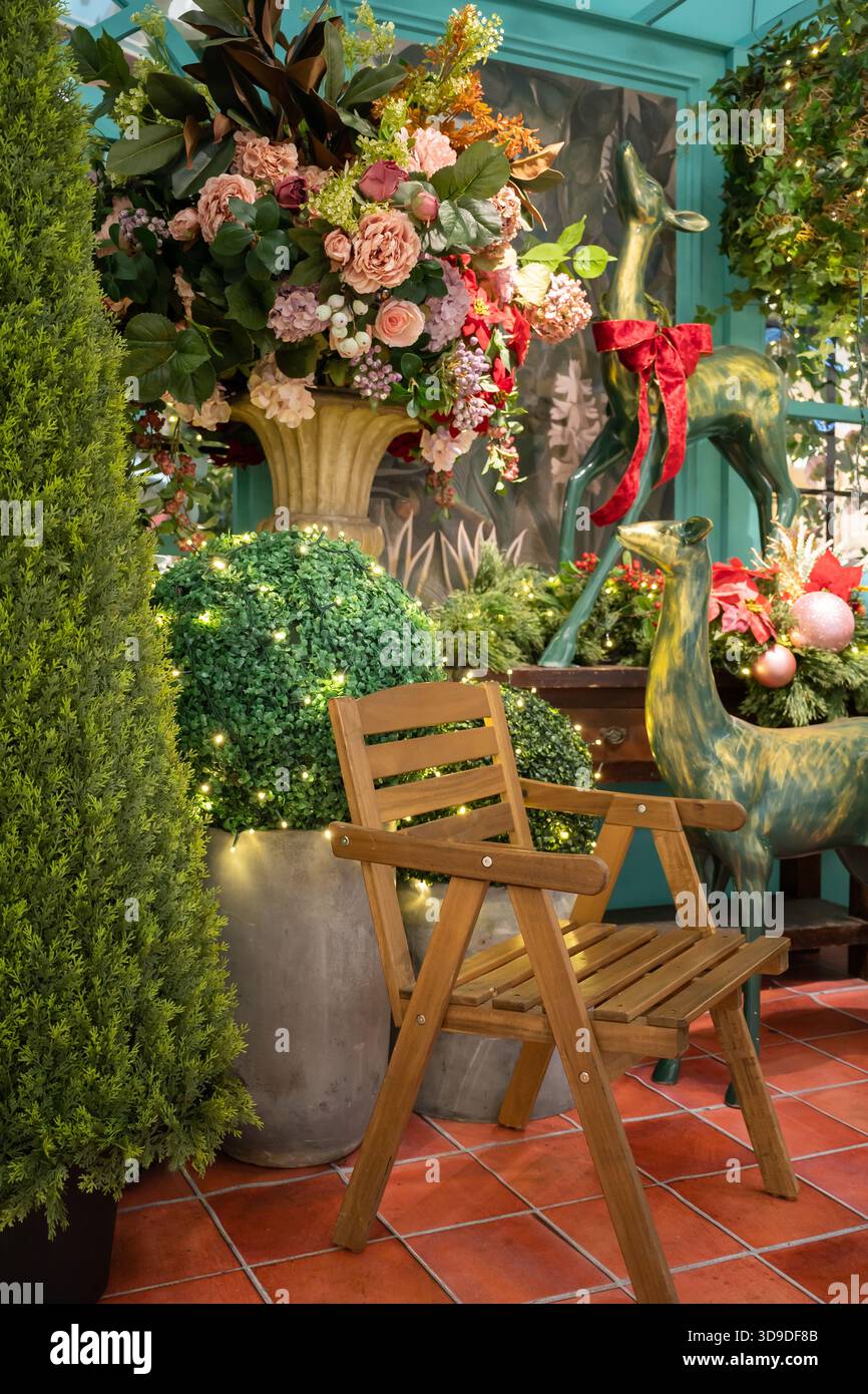 Une scène de jardin extérieur confortable avec une chaise en bois, des bouquets de fleurs vibrants, une végétation luxuriante et des statues décoratives, parfait pour la décoration de jardin Banque D'Images