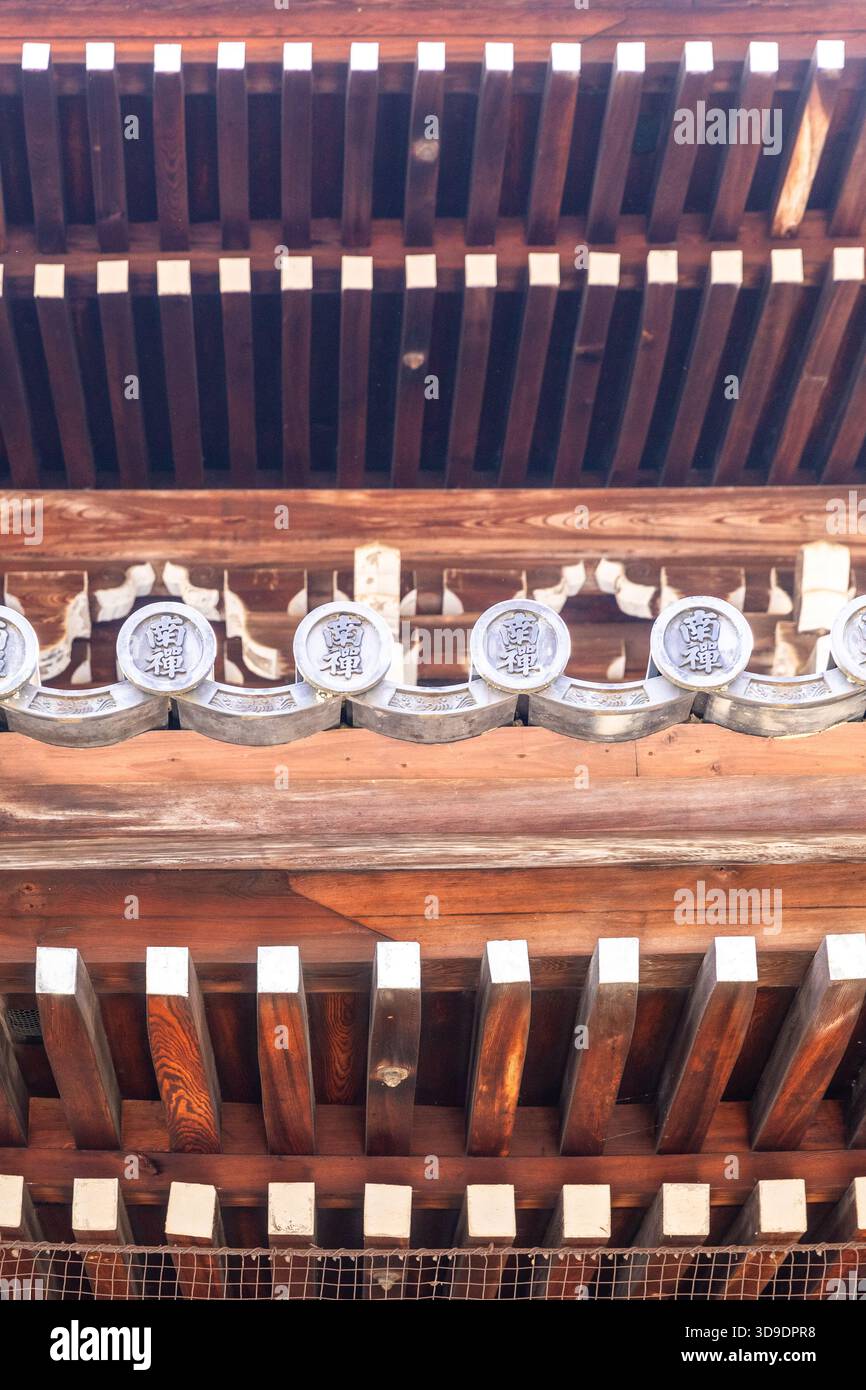 Gros plan d'une gargouille de tuile de toit (Oni-gawara) inscrite 'Nanzen' flanquée de chevrons en bois, Nanzen-ji Banque D'Images