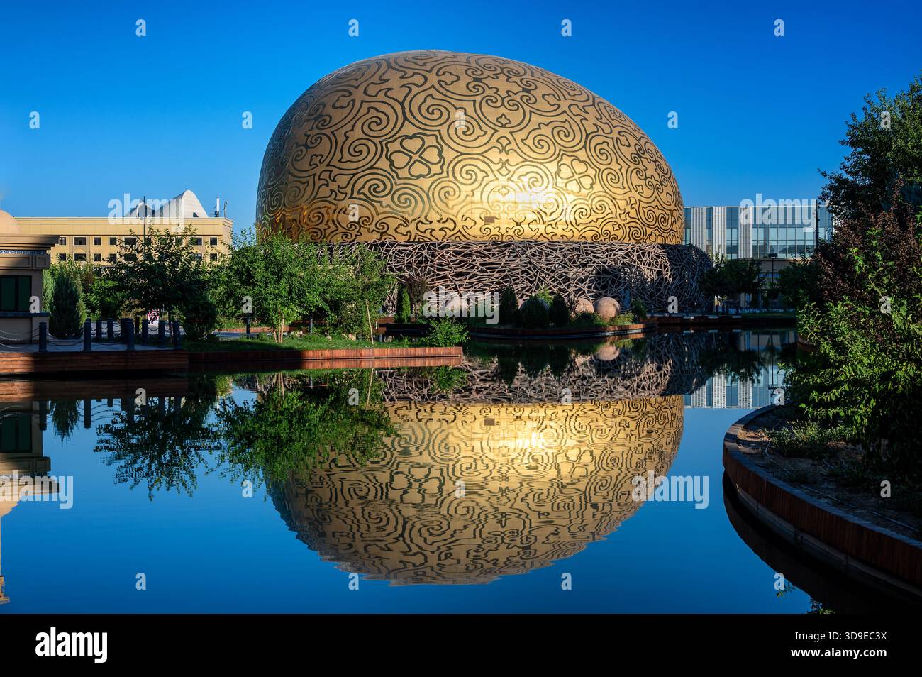 Le bâtiment moderne du Théâtre volant Samruk reflété dans l'eau au Turkestan, Kazakhstan, créant une composition architecturale symétrique. Banque D'Images