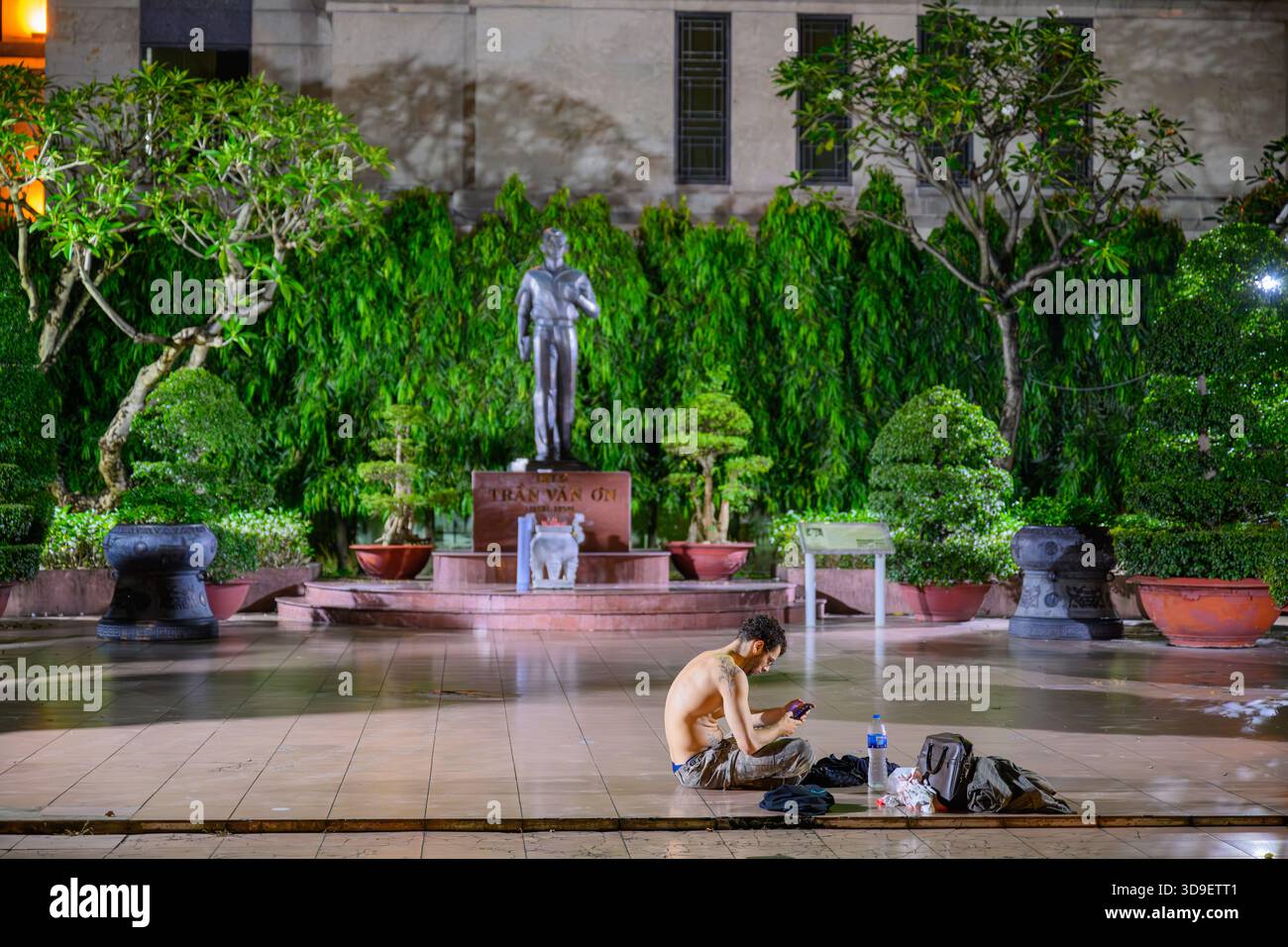 Un touriste assis sur le sol la nuit dans le parc Bách Tùng Diệp, Ho Chi Minh ville, Vietnam Banque D'Images