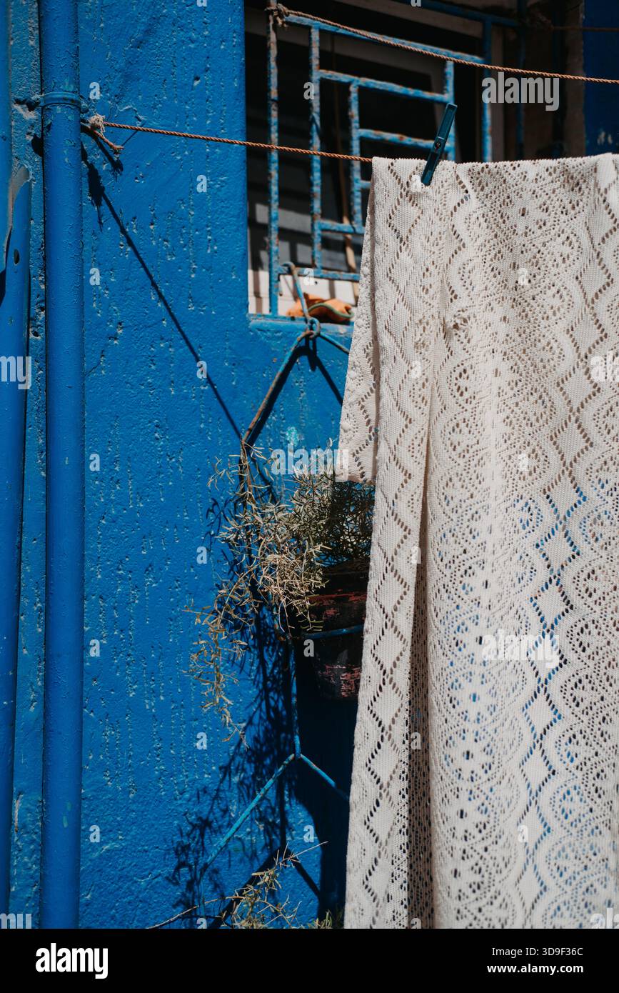 Tissu crochet blanc séchage contre mur bleu à Taghazout, Maroc Banque D'Images