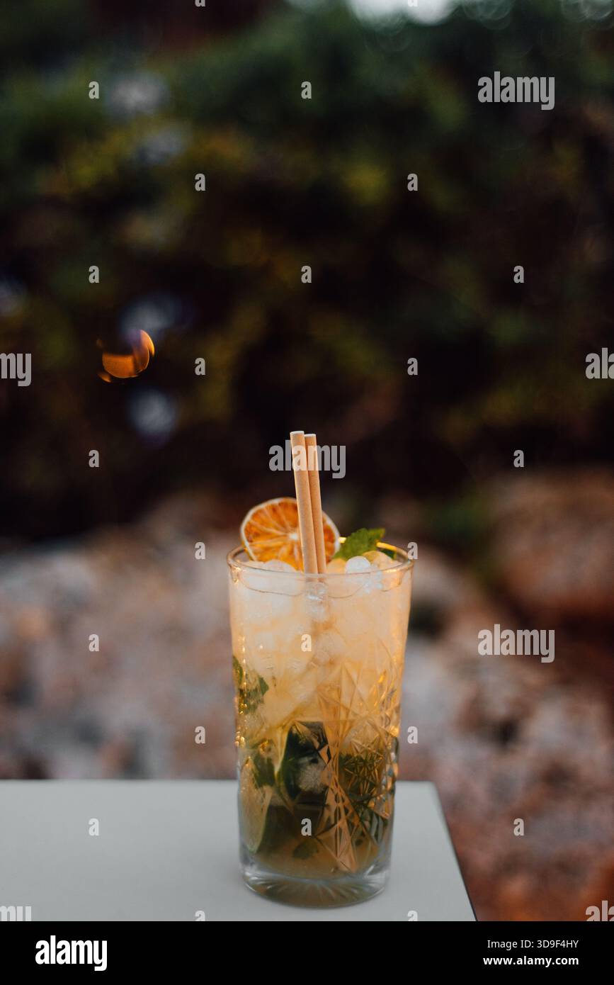 Cocktail Mojito rafraîchissant avec menthe et citron vert au coucher du soleil en plein air Banque D'Images