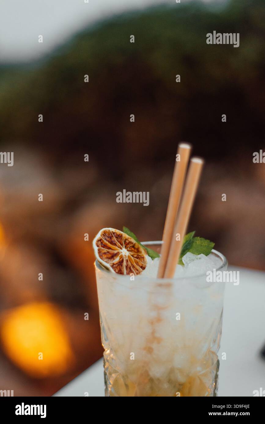 Gros plan du cocktail Mojito avec menthe et garniture de citron vert séché au coucher du soleil Banque D'Images
