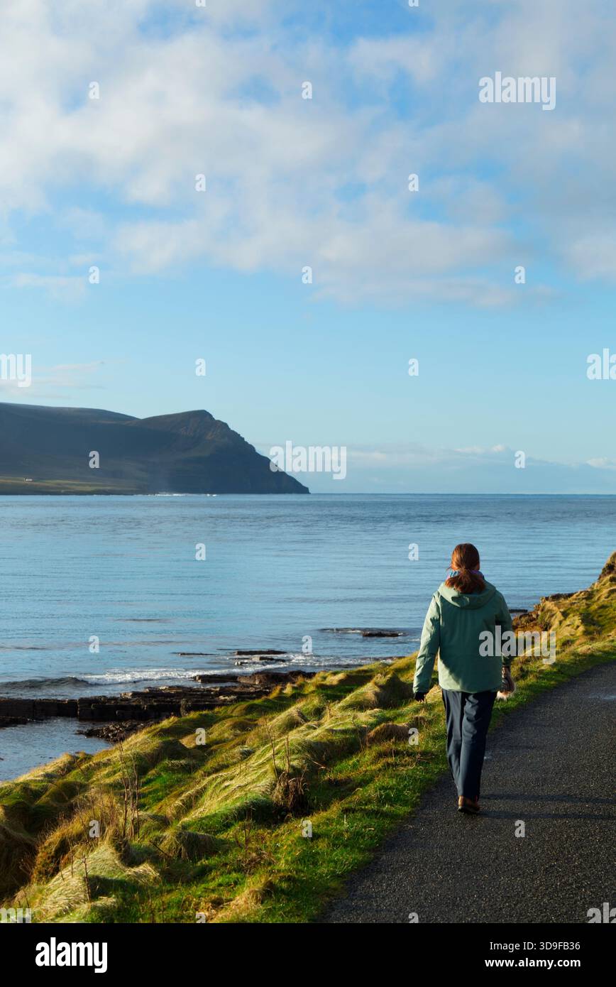 Femme appréciant la promenade côtière le jour calme de l'hiver, Orcades Islands Banque D'Images