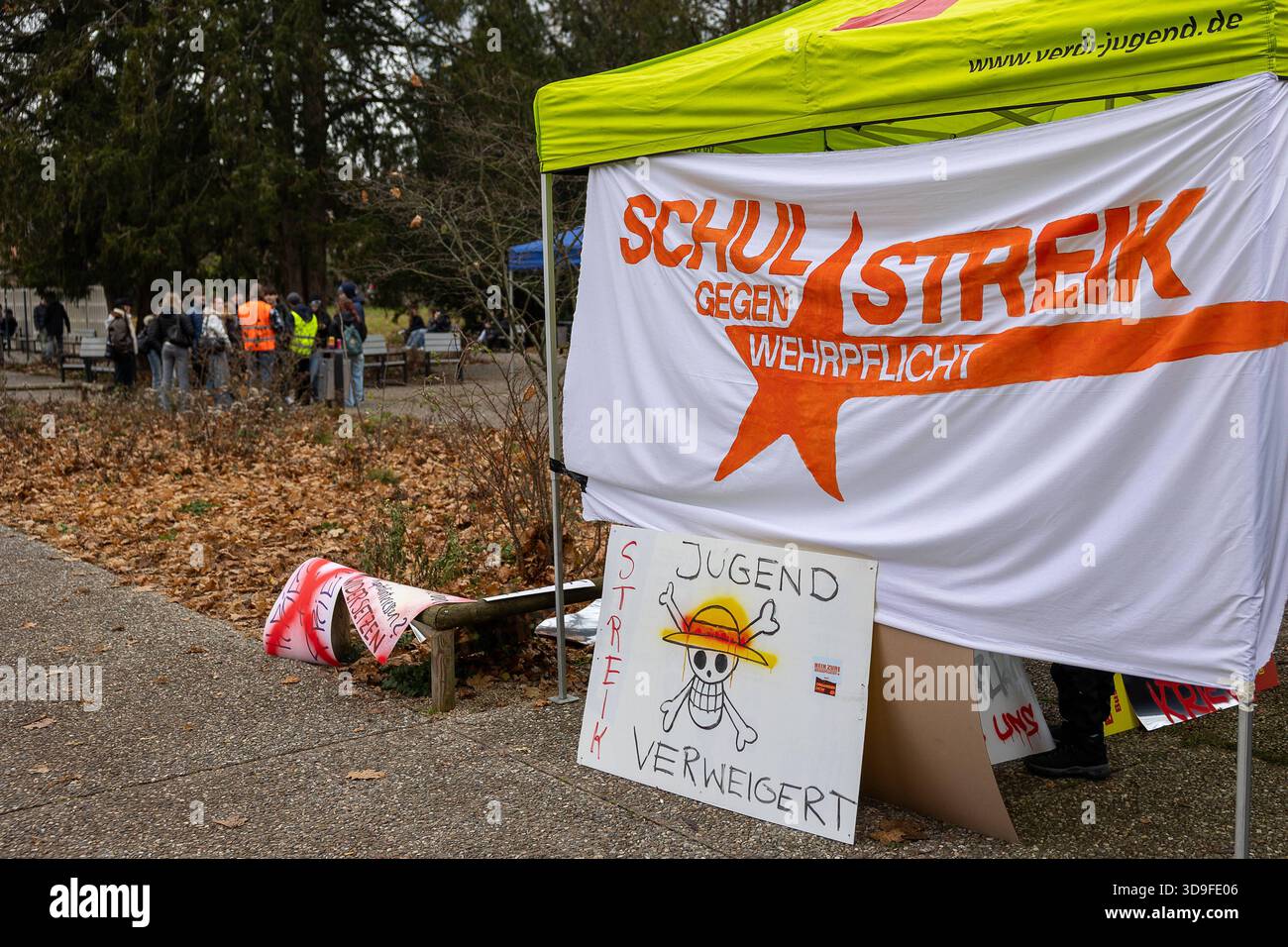 Schulstreik gegen Wehrdienst, Nürnberg, 05.12.2025 Informationsstand der Verdi-Jugend mit einem großen Banner Schulstreik gegen Wehrpflicht im Cramer-Klett-Park in Nürnberg. Davor ein handgemaltes Schild mit dem slogan Jugend verweigert und einer Zeichnung angelehnt an das logo der Serie One Piece. IM Hintergrund versammeln sich Teilnehmer*innen der Aktion zu einer Protestkundgebung gegen das geplante Wehrdienst-Modernisierungsgesetz. Nürnberg Bayern Deutschland *** grève scolaire contre le service militaire, Nuremberg, 05 12 2025 kiosque d'information de la Jeunesse Verdi avec une grande bannière École str Banque D'Images