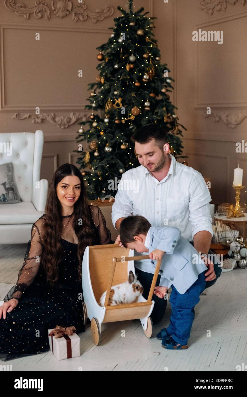 Une famille se réunit dans leur salon joliment décoré, célébrant les vacances avec leur lapin de compagnie. Banque D'Images