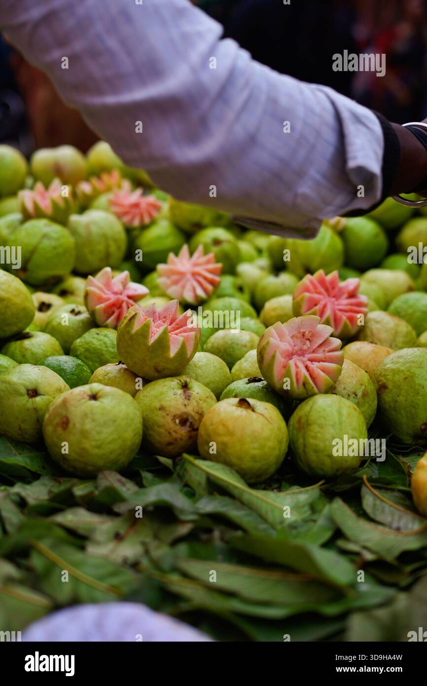 Vendeur de fruits de goyave coupe les fruits de manière designer. Banque D'Images