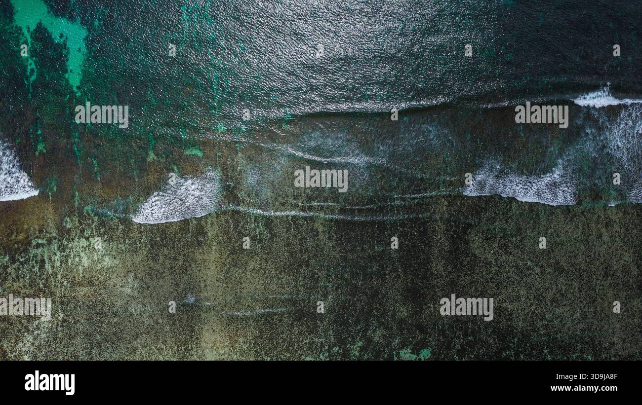 Structure de corail submergée avec des vagues brisantes et une surface océanique chatoyante Banque D'Images