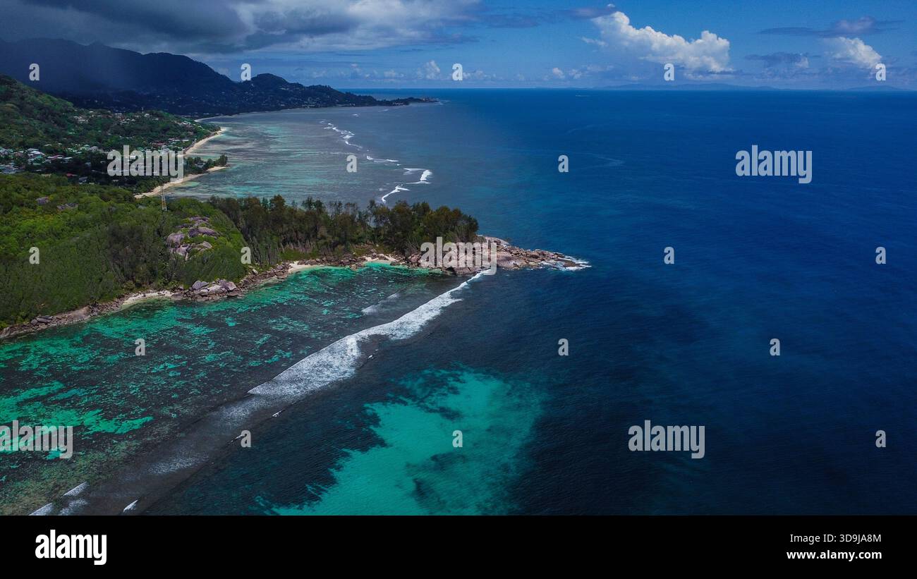 Littoral tropical dynamique avec récifs peu profonds, ciel sombre et océan bleu profond Banque D'Images