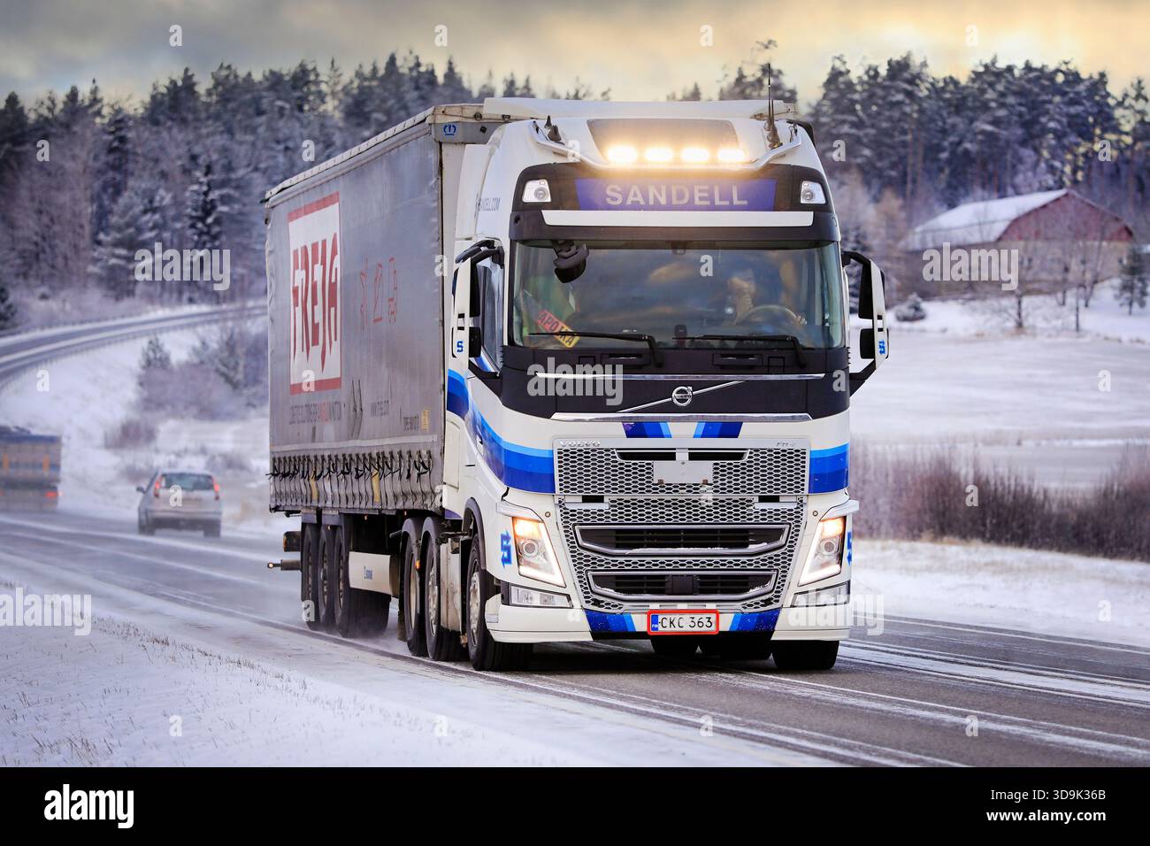 Bleu blanc Volvo FH semi-remorque camion Kuljetusliike Harri Sandell Oy avec des phares lumineux sur la route 52 au crépuscule d'hiver. Salo, Finlande. 27 décembre 2021. Banque D'Images