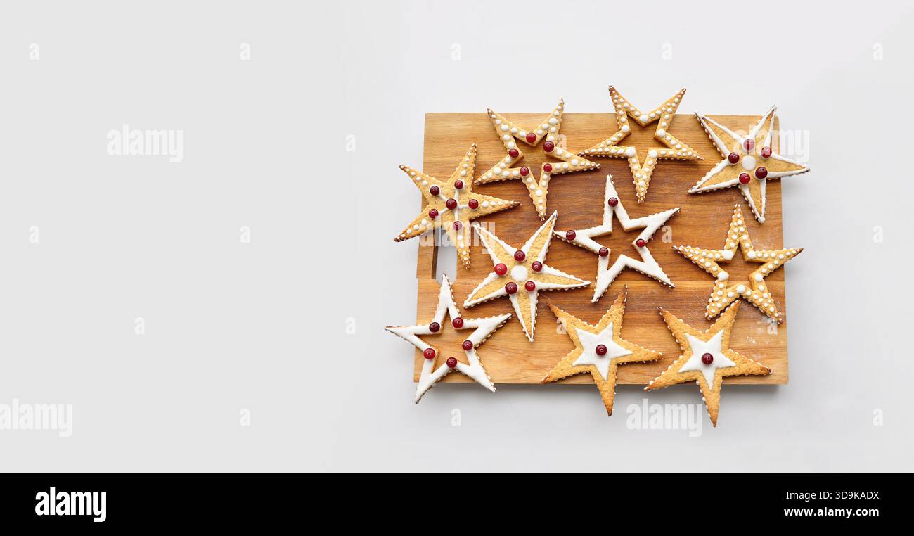 Gâteries de Noël, nourriture funky, cadeaux faits main, amour. Planche à découper isolée en bois avec biscuits en forme d'étoile, émaillée et décorée Banque D'Images