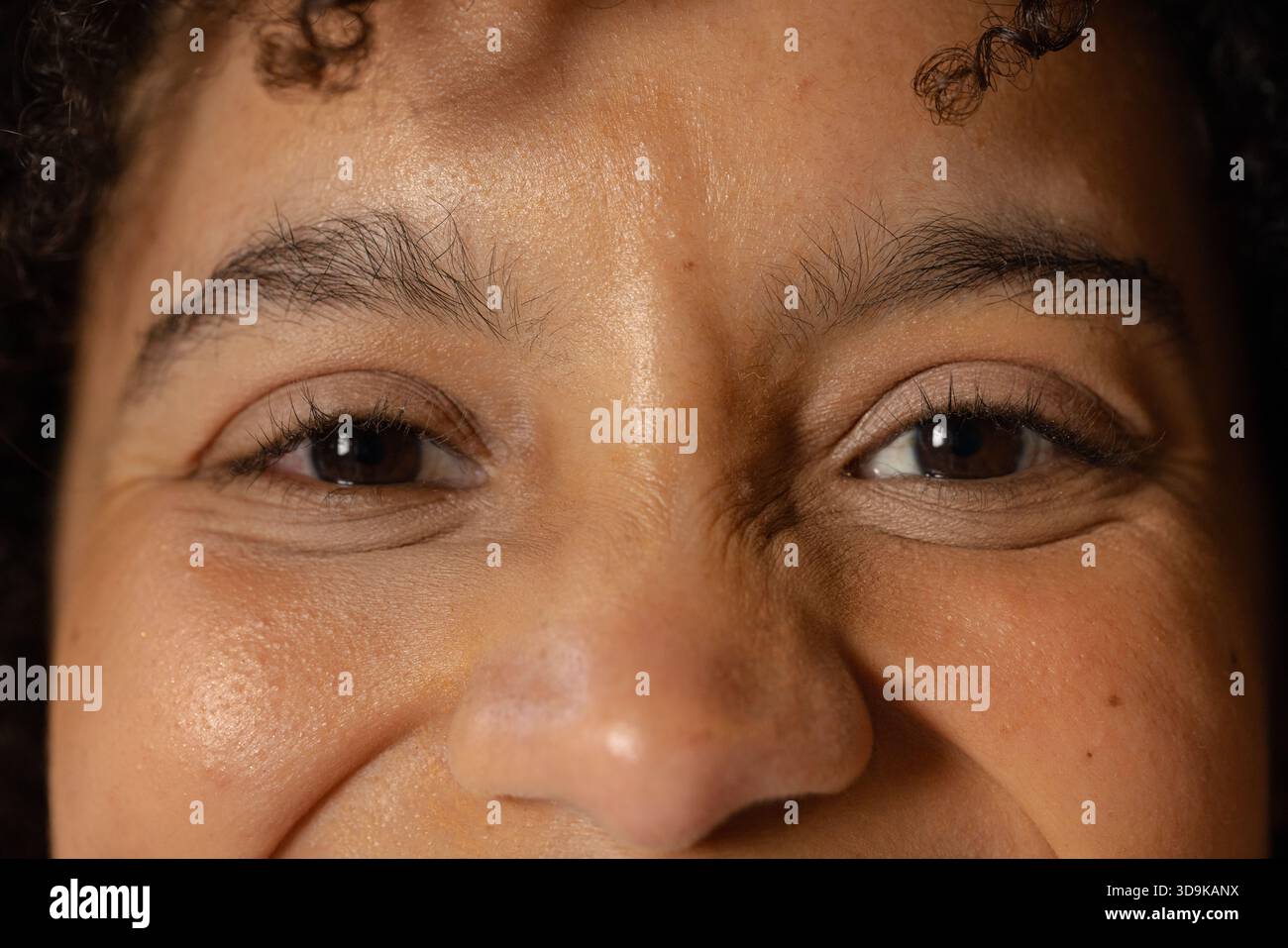 Femme afro-américaine présentant des lignes fines plissant les coins des yeux sous un éclairage de studio focalisé Banque D'Images