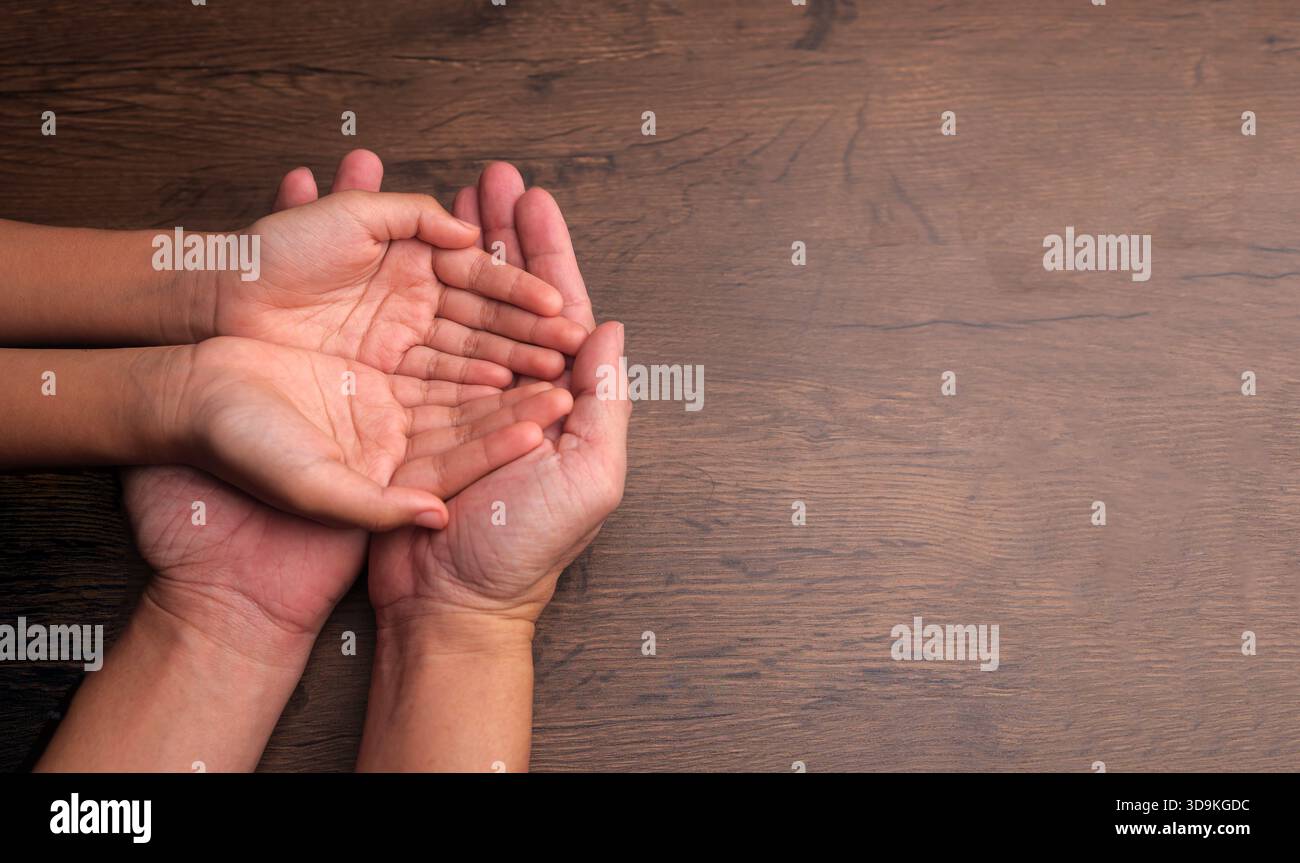 Les mains ouvertes d'un père et d'un enfant superposés, représentant les soins, la confiance, l'orientation et le lien significatif trouvé dans les familles monoparentales buil Banque D'Images