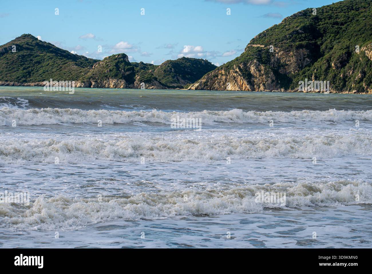 Paysage pittoresque de collines verdoyantes et de falaises tombant dans une mer agitée sous un ciel bleu avec des nuages à la plage d'Agios Georgios Pagon à Corf Banque D'Images