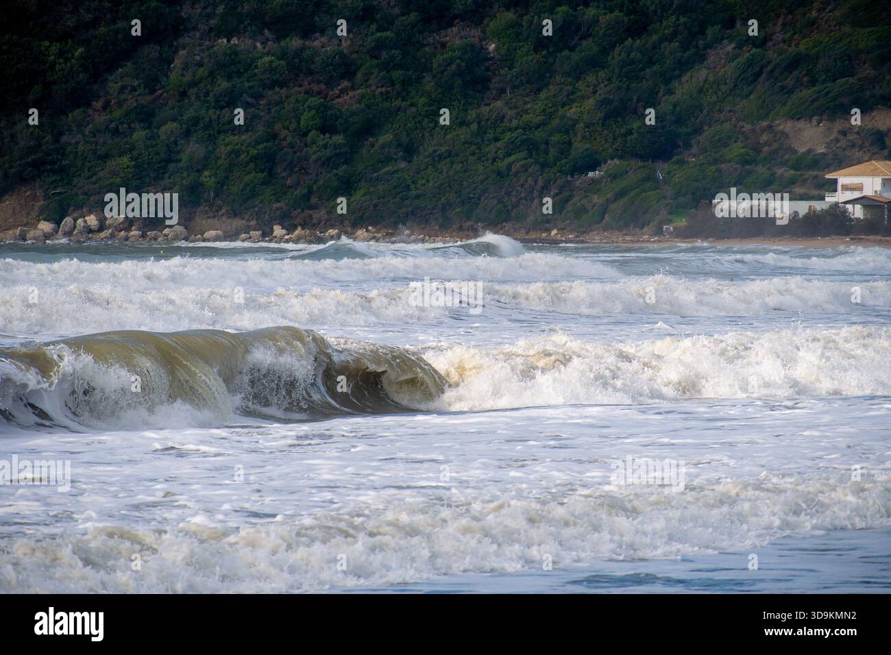 Photo téléphoto de grandes vagues boueuses s'écrasant avec force sur le rivage lors d'une tempête hivernale à Corfou en Grèce mettant en évidence la puissance brute de la nature et da Banque D'Images