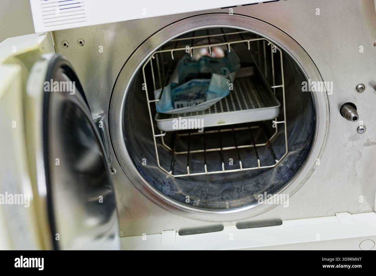 Une petite porte ronde révèle le stérilisateur compact avec des étagères pour les ensembles emballés. Des indicateurs et une poignée ferme marquent la fin de la pression et de la vapeur c. Banque D'Images