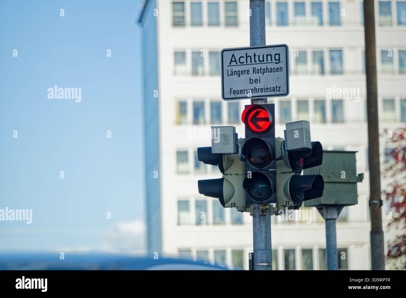 Un poteau simple porte deux feux de circulation opposés avec un texte d'avertissement ci-dessous, la flèche gauche s'allume en rouge, le message indique aux conducteurs de t Banque D'Images