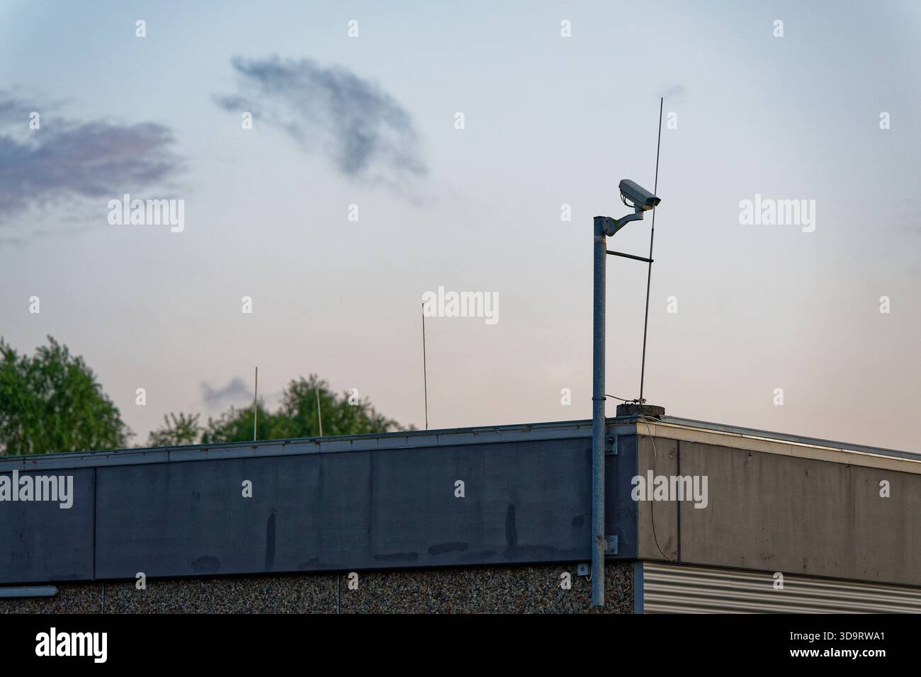 Un tuyau métallique sur le toit supporte une seule caméra de sécurité dirigée sur le bord et regardant la rue ci-dessous, la configuration ressemble à simple constant sur Banque D'Images