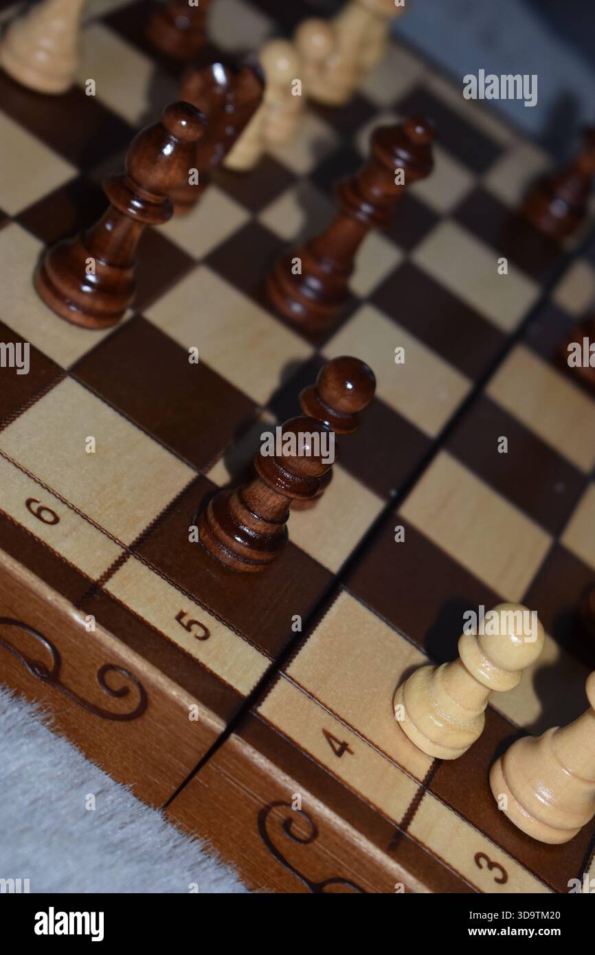 Pièces d'échecs noires et blanches sur un échiquier en bois Banque D'Images