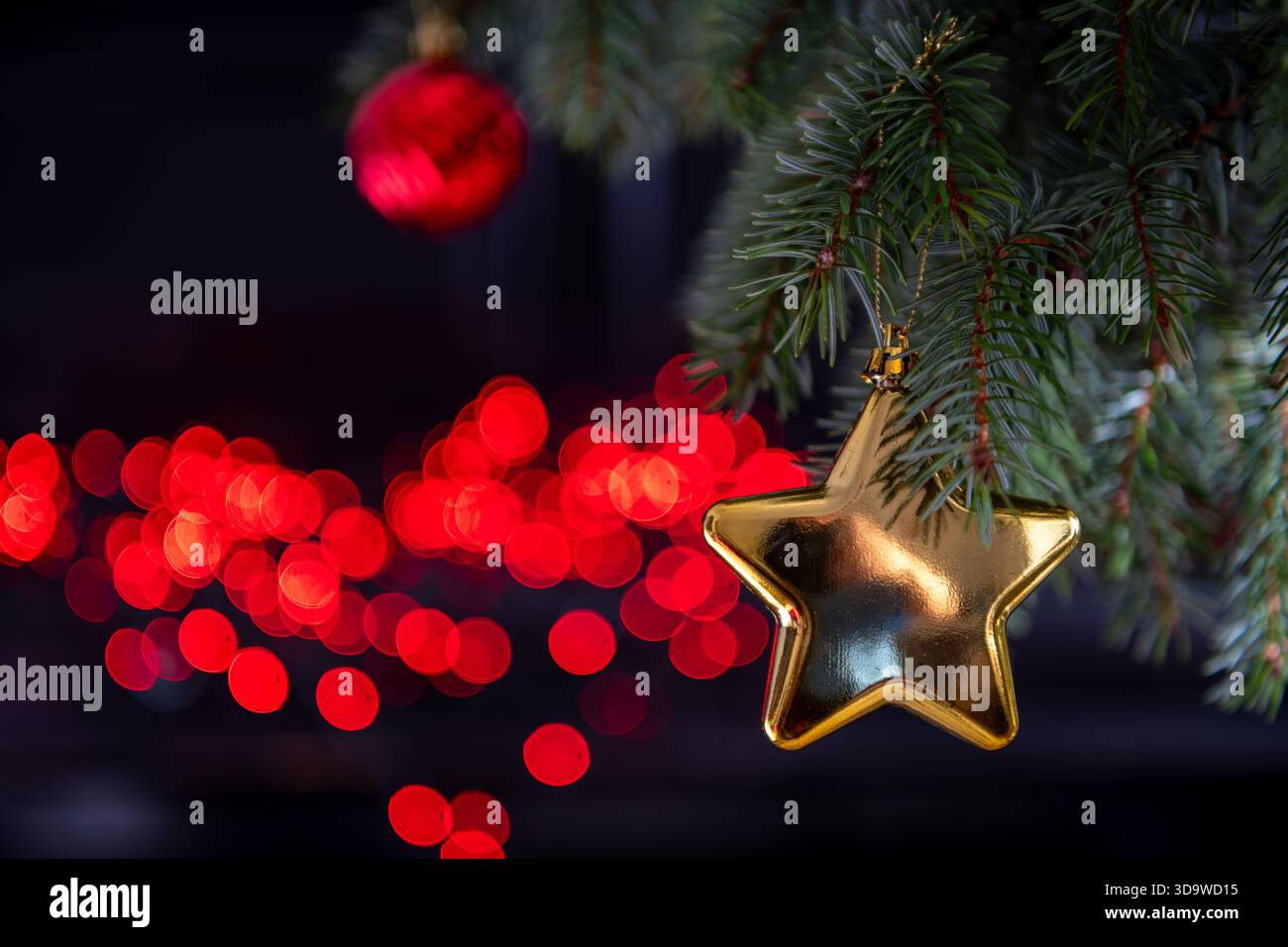 Un fond de Noël avec des ornements suspendus sur un sapin et des lumières dans le fond sombre. Banque D'Images