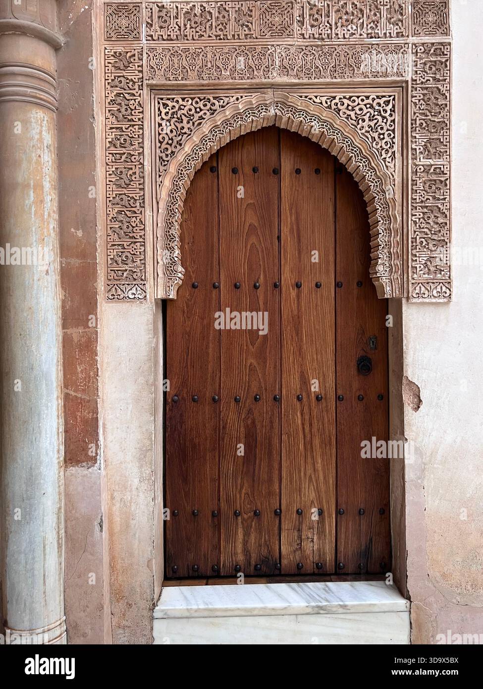 Porte en bois ornée avec arc en stuc sculpté à l'intérieur du palais de l'Alhambra, Grenade, Espagne, mettant en valeur l'architecture mauresque et islamique. Banque D'Images