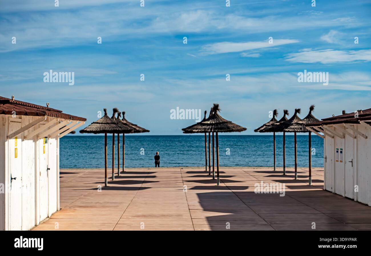Une vue symétrique des parasols de plage en paille et des cabanes blanches à Fuengirola, Espagne. La scène présente la mer Méditerranée Banque D'Images
