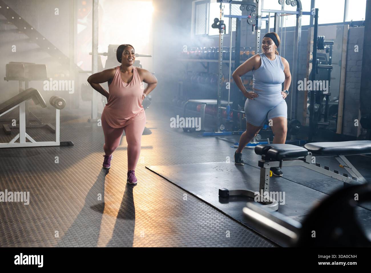 Diverses femmes mi-adultes se lançant sur le sol en caoutchouc de la salle de sport dans des vêtements d'activité et des baskets assortis, banc Banque D'Images