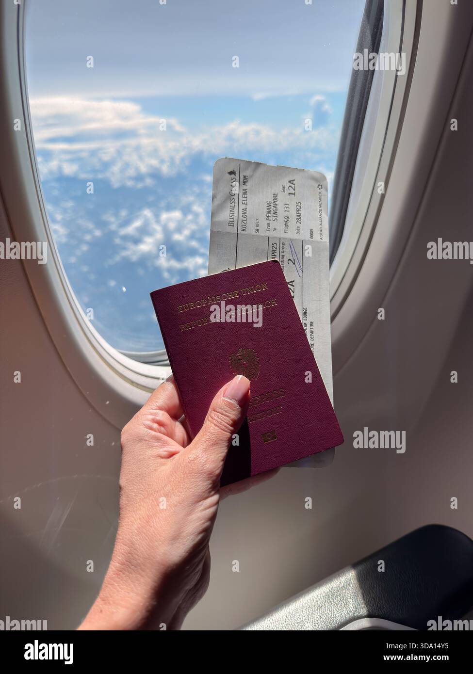 Penang, Malaisie - 28 avril 2025 : un passager est vu avec un passeport et une carte d'embarquement avec des nuages à l'extérieur de la fenêtre de l'avion pendant le fligh Banque D'Images
