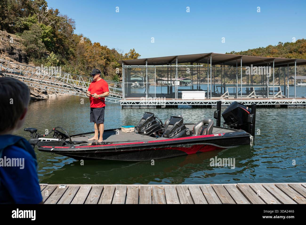 garçon debout sur le pont et regardant papa pêcher hors du bateau de basse Banque D'Images
