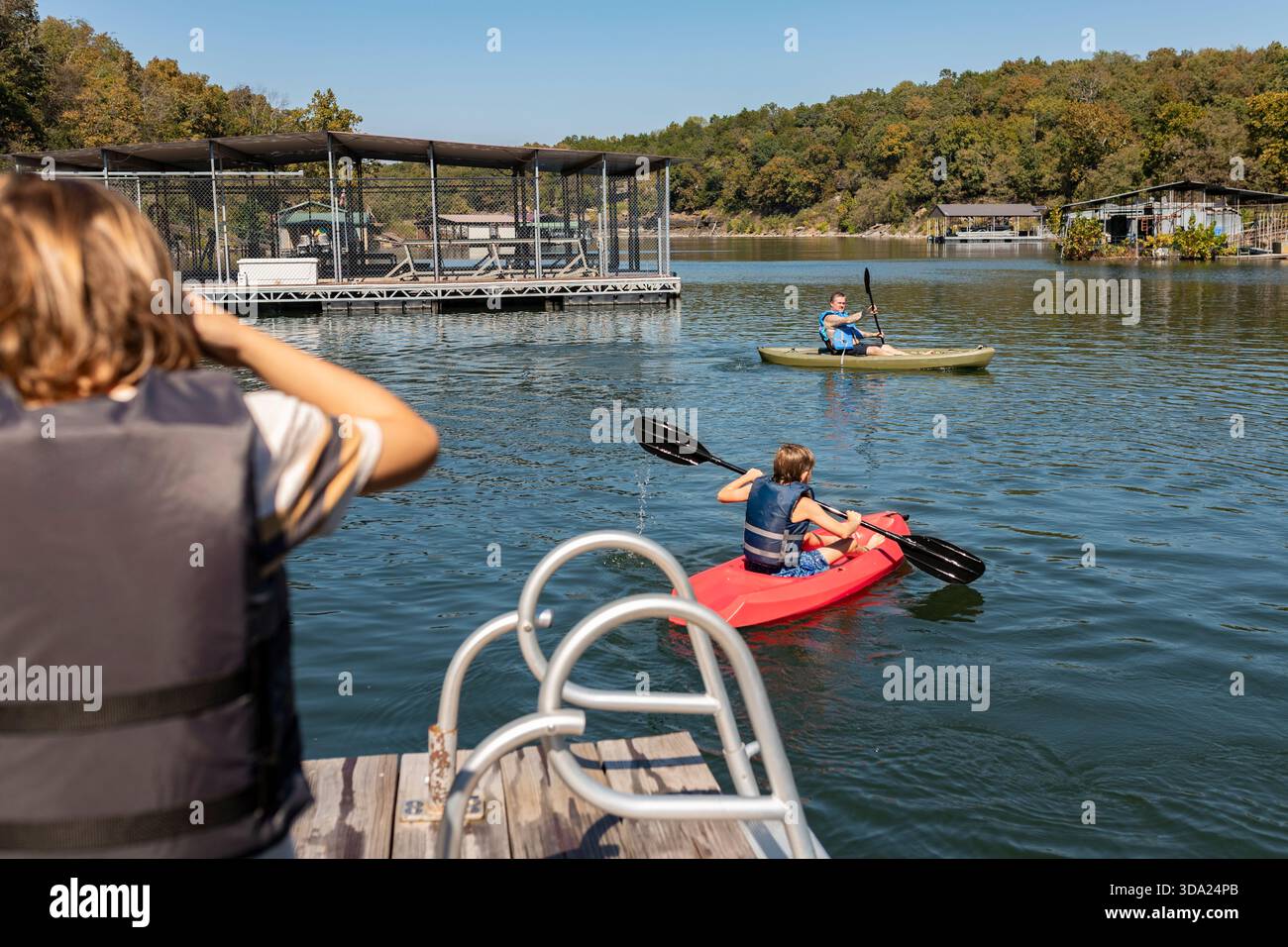 garçon regardant frère et papa kayak sur le lac Banque D'Images