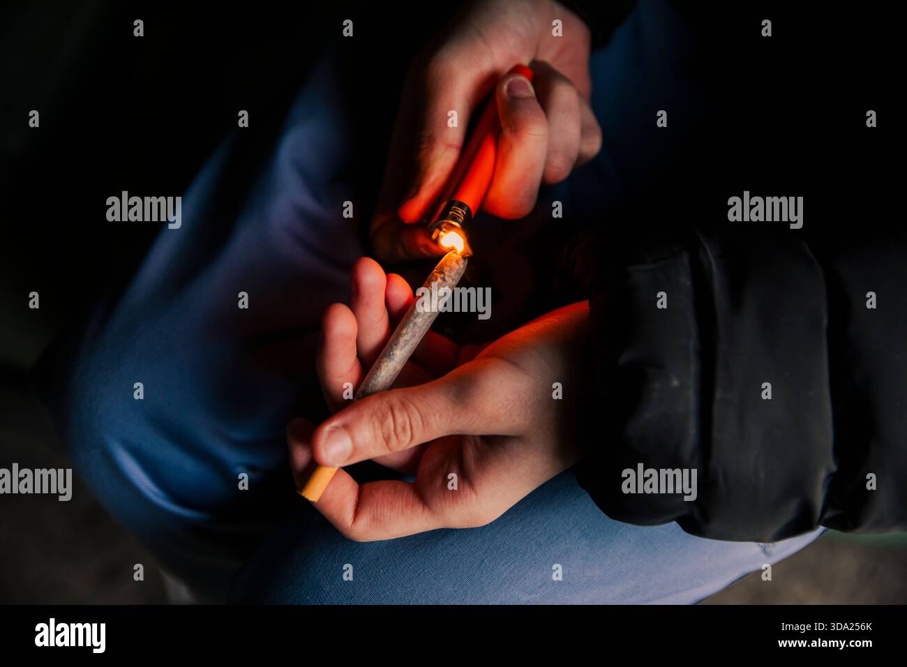 Les mains d'un homme allumant une cigarette de marijuana avec un briquet Banque D'Images