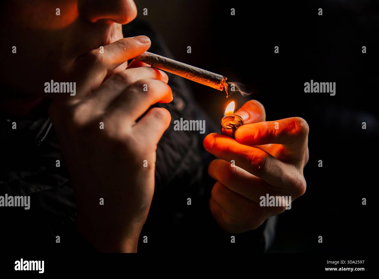 Gros plan d'un homme méconnaissable allumant un joint de cannabis avec une flamme Banque D'Images