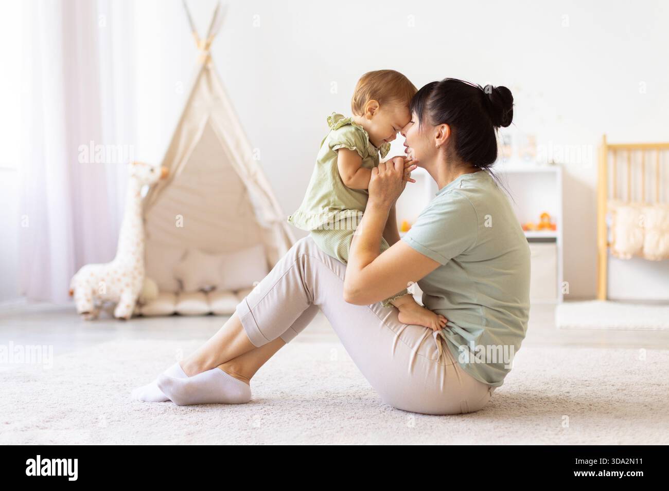 Mère assise sur le sol tenant son bébé près de lui lorsqu'ils touchent le front Banque D'Images