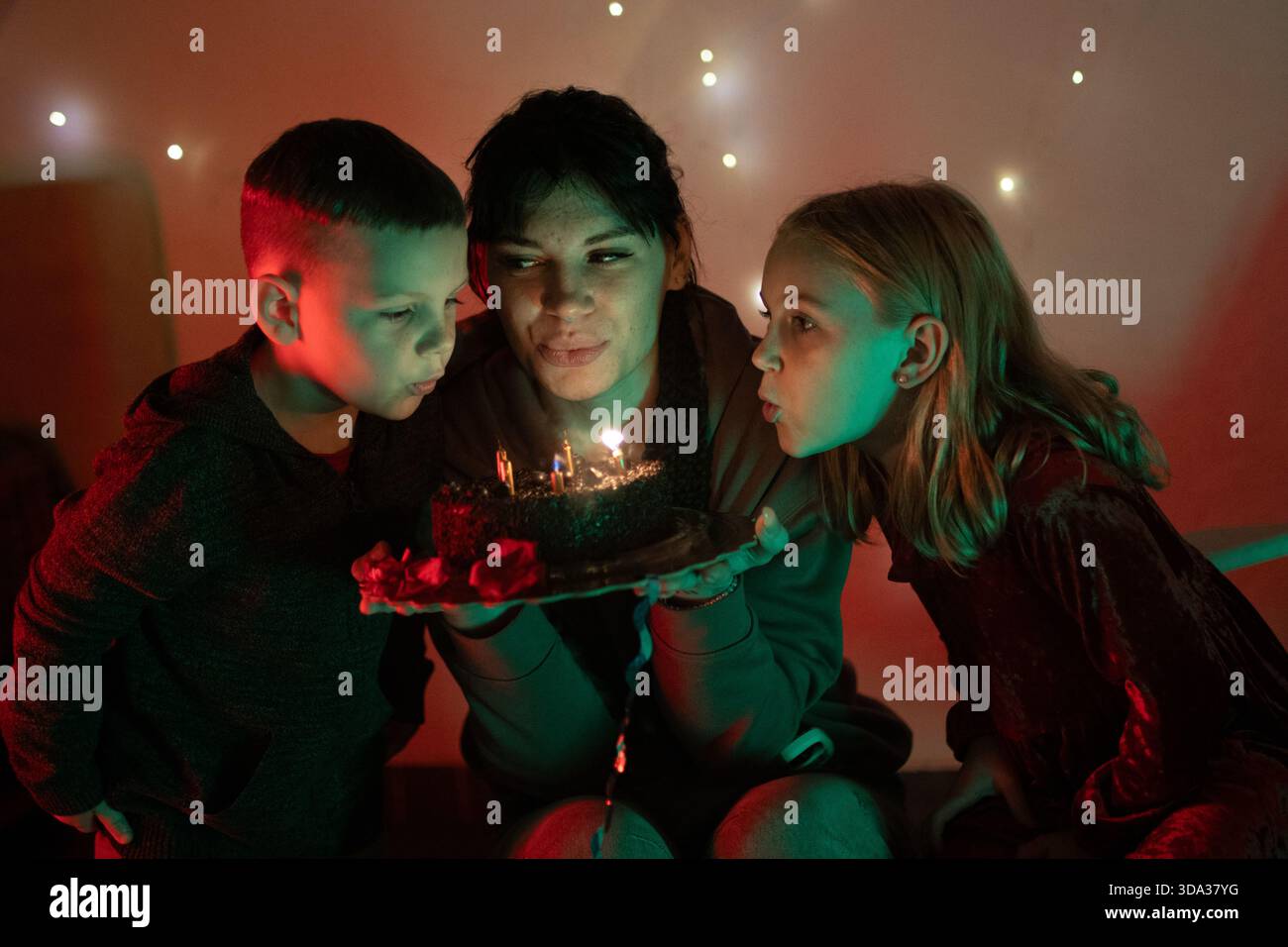 Famille soufflant des bougies d'anniversaire sur un gâteau au chocolat Banque D'Images
