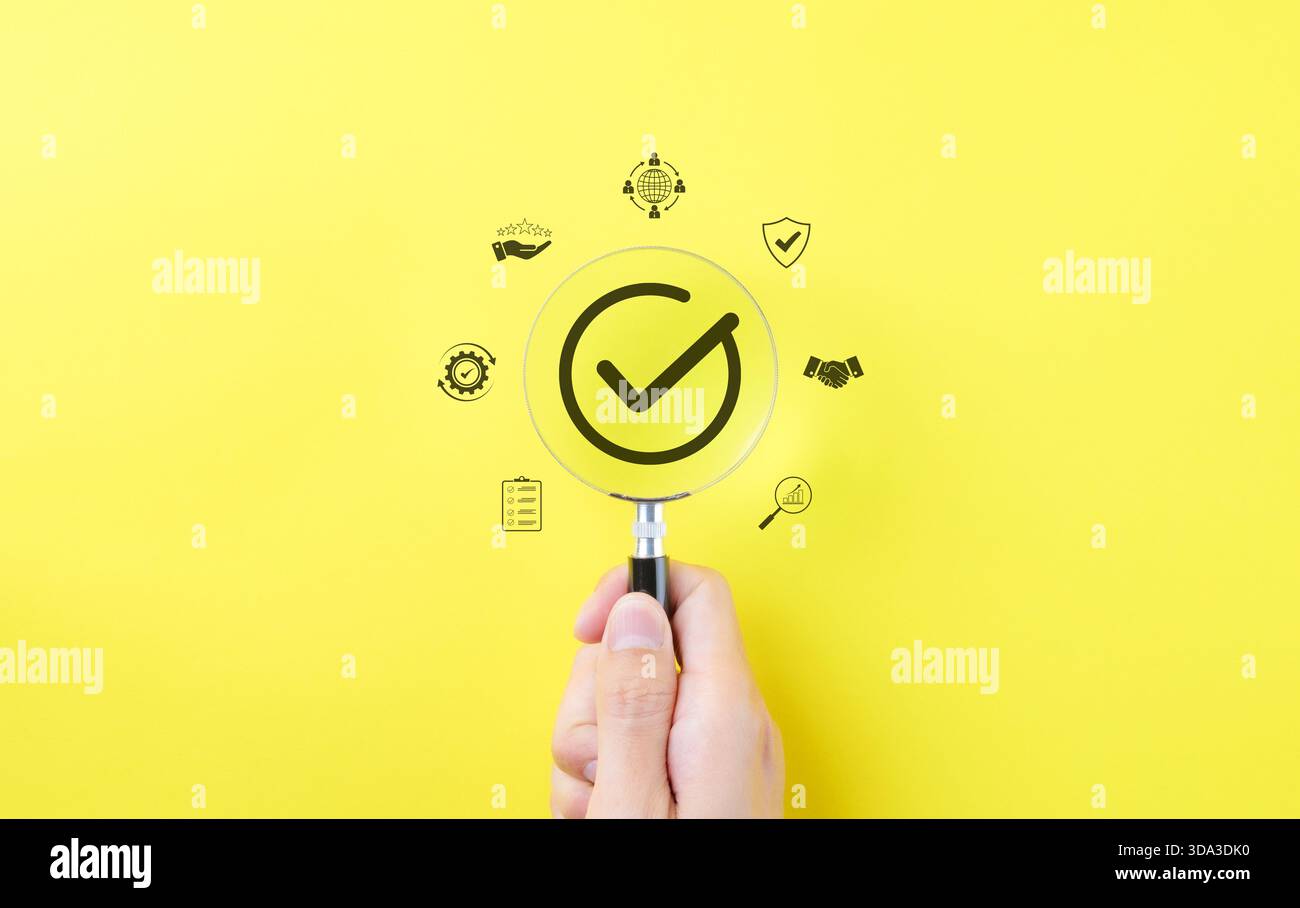 Concept d'assurance qualité, marque de contrôle de conformité. Main tenant la loupe avec un symbole de coche avec des icônes représentant l'assurance qualité, co Banque D'Images