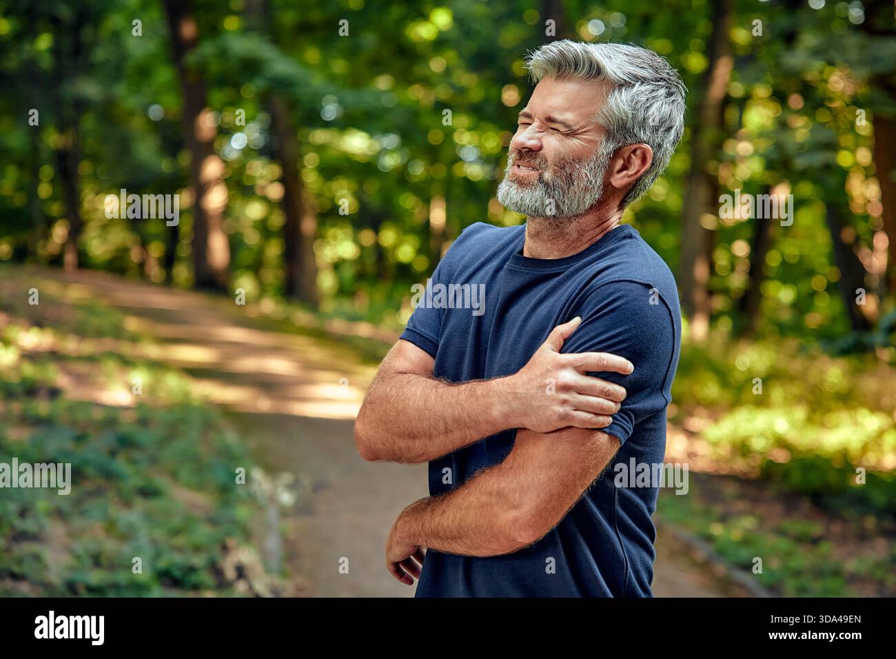 Dans une forêt tranquille, la douleur à l'épaule d'un homme reflète ses sentiments complexes sur la guérison, la promotion de la pleine conscience et une connexion plus profonde avec la nature, enc Banque D'Images