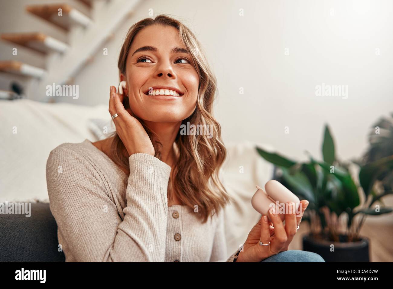 Jeune femme écoutant de la musique ou une leçon audio dans un casque tout en étant assise sur le sol près du canapé dans le salon à la maison. Banque D'Images