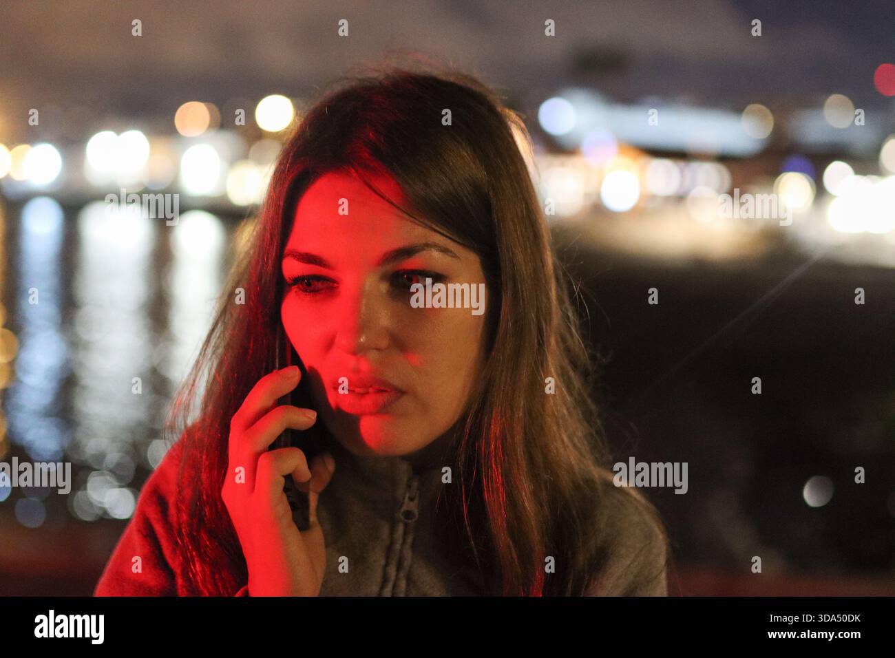 Jeune femme recevant un appel téléphonique urgent de lumière rouge Banque D'Images