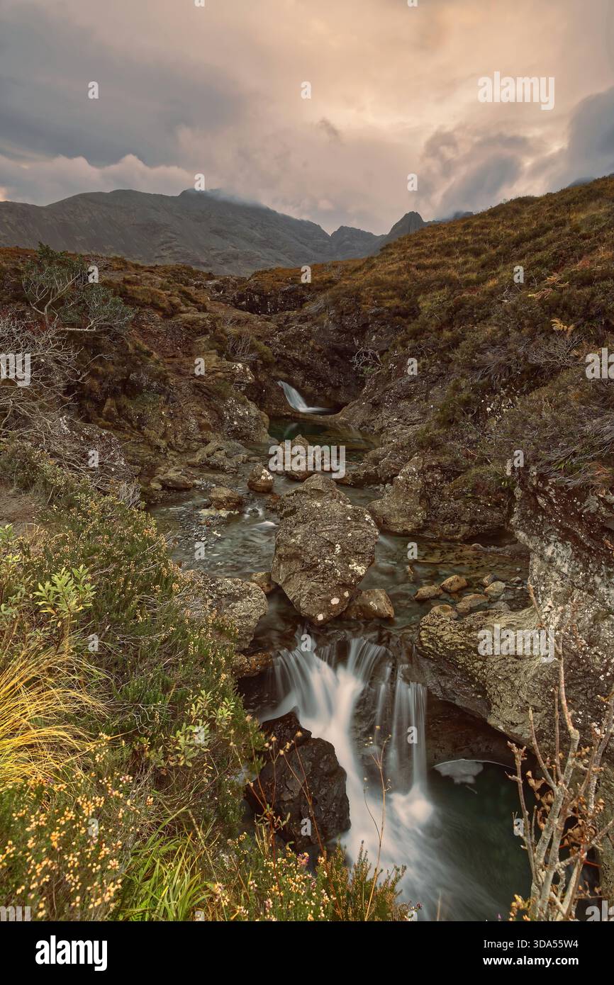 129 Allt Coir a' Mhadaidh Burn Cascading at Fairy Pools, Bruach na Frithe-Sgùrr na Bàirnich-Sgùrr an Fheadain Peaks in background (G-d). Skye-Scotland Banque D'Images