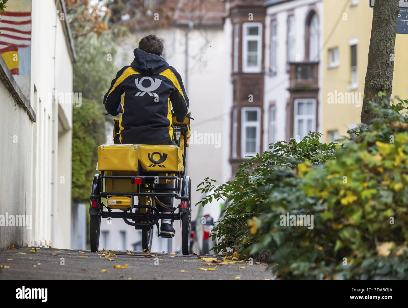 Deutsche Post mailmen sur un vélo à travers la ville. Stuttgart, Bade-Wuerttemberg, Allemagne Banque D'Images